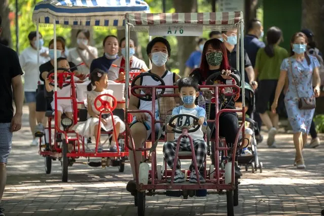 Adults and children ride pedal cycles at a public park in Beijing, Saturday, August 21, 2021. China will now allow couples to have a third child as the country seeks to hold off a demographic crisis that threatens its hopes of increased prosperity and global influence. (Photo by Mark Schiefelbein/AP Photo)