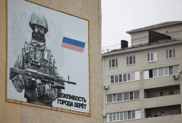 A banner depicting a Russian serviceman, is seen on a military barrack building at the base of 247th Air Assault Regiment in the southern city of Stavropol, Russia, February 25, 2016. The banner reads, “Politeness wins the cities”. (Photo by Eduard Korniyenko/Reuters)