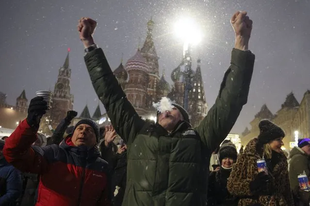 People gather near Red Square with the St. Basil's Cathedral, right, and the Spasskaya Tower, left, in the background, to celebrate the new year after midnight in Moscow, Russia, Monday, January 1, 2024. (Photo by Marina Lystseva/AP Photo)