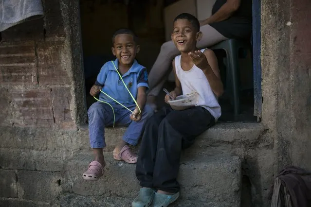 Carlos, 8, and Yoiner, 5, sit at the door of their home, late afternoon in the Petare slum of Caracas, Venezuela, Thursday, February 7, 2019. (Photo by Rodrigo Abd/AP Photo)