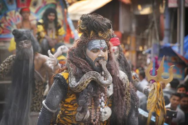 A devotee dressed as Lord Shiva puts a snake in his mouth during a procession to mark Mahashivratri festival in Prayagraj, Uttar Pradesh state, India, Monday, March 4, 2019. “Shivaratri”, or the night of Shiva, is dedicated to the worship of Lord Shiva, the Hindu god of death and destruction. (Photo by Rajesh Kumar Singh/AP Photo)