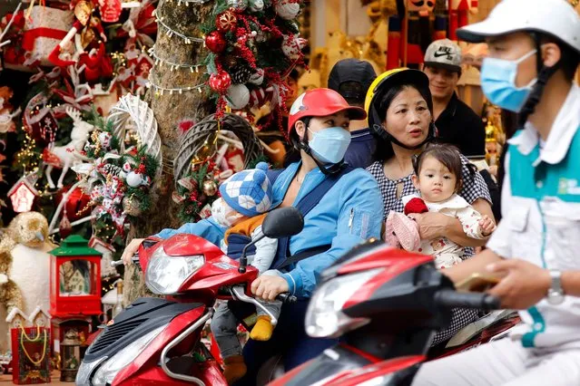 People ride motorbikes past a shop selling Christmas decorations on a street in Hanoi, Vietnam on December 15, 2023. Christmas is considered as one of the main annual religious festivals in Vietnam, with many consumers shopping for gifts and decorations leading up to 25 December, as well as various festive activities held during Christmas time. (Photo by Luong Thai Linh/EPA/EFE)