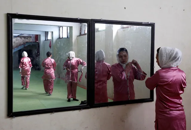 Hatifa Rezai (R), 19, a student of the Shaolin Wushu club, is reflected in a mirror as she adjusts her scarf before her exercise in Kabul, Afghanistan January 19, 2017. (Photo by Mohammad Ismail/Reuters)