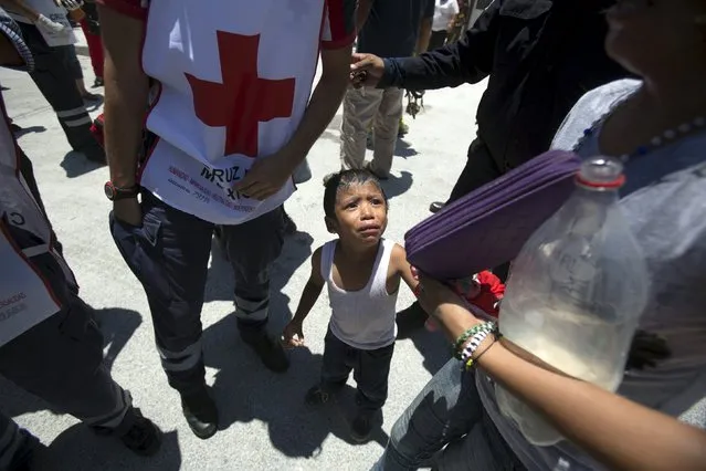 A child experiencing shock is seen next to a Red Cross paramedic outside the jail during a clash of rival groups in the prison of Cancun, Mexico April 26, 2015. (Photo by Victor Ruiz Garcia/Reuters)