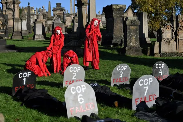 Performers from the Red Rebels conduct a funeral ceremony at Glasgow Necropolis to symbolise the failure of the COP26 process, at Glasgow Cathedral in Glasgow on November 13, 2021, during the COP26 UN Climate Change Conference. (Photo by Paul Ellis/AFP Photo)