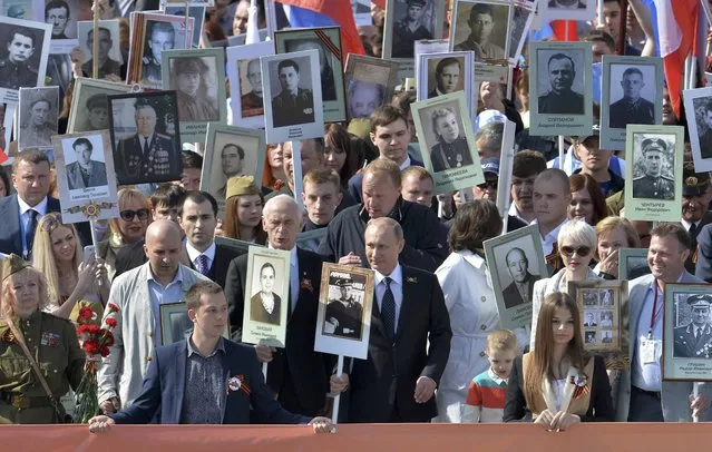 Russian President Vladimir Putin (C) holds the portrait of his father as he takes part in the Immortal Regiment march with pictures of World War Two soldiers on Red Square during the Victory Day celebrations in Moscow, Russia, May 9, 2015. (Photo by Reuters/Host Photo Agency/RIA Novosti)