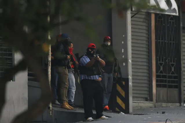 Armed and masked supporters of President Nicolas Maduro stand at an entrance of the Transportation Ministry in Caracas, Venezuela, Tuesday, April 30, 2019, during a military uprising attempt to oust Maduro. (Photo by Fernando Llano/AP Photo)