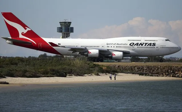 In the August 20, 2015, file photo people people watch from a beach as a Qantas plane taxies on the runway at Sydney Airport in Sydney, Australia. International tourists won't be welcomed back to Australia until next year, with the return of skilled migrants and students given higher priority, the prime minister said on Tuesday, Oct. 5, 2021. (Photo by Rick Rycroft/AP Photo/File)