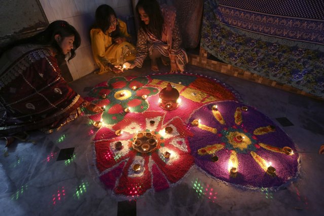 Hindu women attend a ceremony to celebrate Diwali, the festival of lights, at a temple in Karachi, Pakistan, Friday, November 4, 2021. The Hindu festival of lights, Diwali celebrates the spiritual victory of light over darkness. (Photo by Fareed Khan/AP Photo)