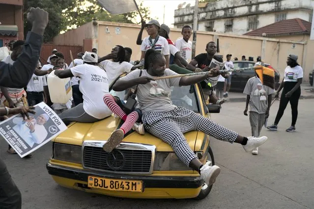 Supporters of the Gambian President Adama Barrow celebrate the partial results that give the lead to their candidate during the counting ballots in Gambia's presidential election, in Banjul, Gambia, Sunday, December 5, 2021. (Photo by Leo Correa/AP Photo)
