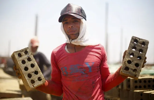 A labourer poses for a photo with bricks at a traditional brick factory in Arab Mesad district of Helwan, northeast of Cairo, May 14, 2015. (Photo by Amr Abdallah Dalsh/Reuters)