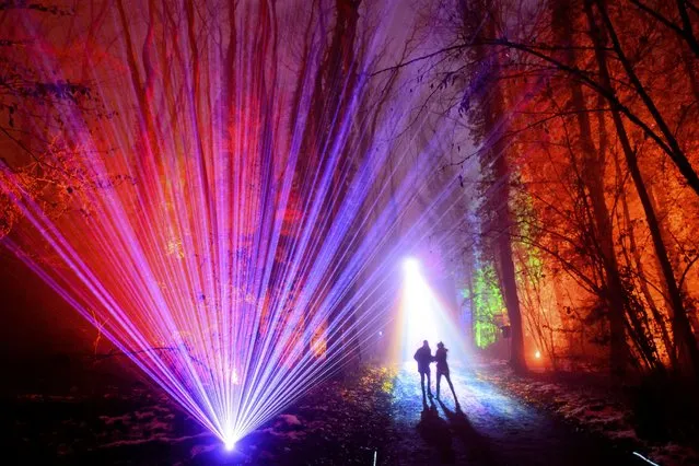 People walk on a one kilometer long path in the illuminated forest during the first Broye Luminis Light Festival, in Lully, Switzerland, Tuesday, December 14, 2021. From December 10 to 19, 2021, Broye Luminis will highlight the forest through an enchanting and multi-sensory journey in the “Bois de la Faye” (Faye forest), located near the Rose de la Broye restoroute in Estavayer-le-Lac. (Photo by Laurent Gillieron/Keystone via AP Photo)