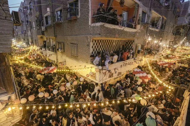Residents of Ezbet Hamada in Cairo's El Matareya district celebrate a mass break fast, “Iftar”, the meal to end their fast at sunset, during the holy fasting month of Ramadan in Cairo, Egypt, Monday, March 25, 2024. (Photo by Amr Nabil/AP Photo)