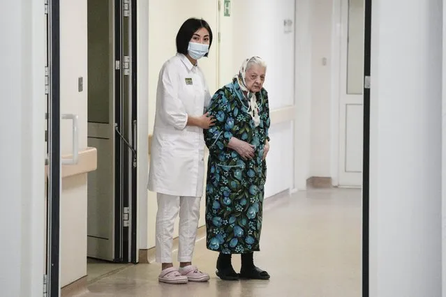 Dr. Saltanat Bekeeva, left, and 101-year-old patient Pelageya Poyarkova enter the hall to speak with media as she leaves the recovery ward for COVID-19 patients at the Federal Center for Brain and Neurotechnology in Moscow, Russia, Friday, December 3, 2021. Russia has reported more than 9.7 million confirmed cases of COVID-19 in the pandemic and more than 270 thousands deaths, which experts believe could be undercounts. (Photo by Pavel Golovkin/AP Photo)