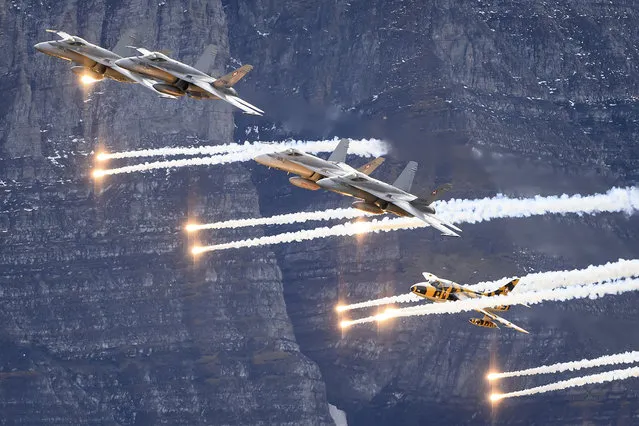 F-18 Hornet jets and an Hawker Hunter T.68 of the Swiss Air Force drops flares during the annual airshow of the Swiss Army in the Axalp ar​ea near Meiringen, Canton of Berne, Switzerland, 21 October 2021. (Photo by Anthony Anex/EPA/EFE)