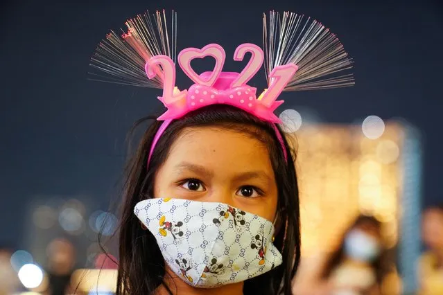 A girl wearing a mask and “2021” headband looks on at a shopping mall as The New Year countdown celebrations and crowded events were banned in Bangkok, Thailand, December 31, 2020. (Photo by Athit Perawongmetha/Reuters)