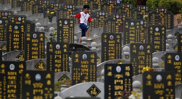 A Chinese boy runs along gravestones during the Qingming Festival outside Kuala Lumpur, Malaysia, on April 5, 2014. The Qingming Festival, or Tomb-Sweeping Day, is an annual festival during which Chinese people honor the dead. (Photo by Associated Press)