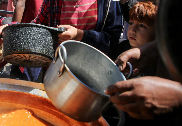 Palestinians gather to receive food cooked by a charity kitchen, amid shortages of aid supplies in Rafah, in the southern Gaza Strip on May 8, 2024. (Photo by Hatem Khaled/Reuters)