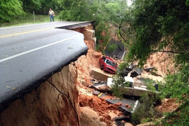 Vehicles rest at the bottom of a ravine after the Scenic Highway collapsed near Pensacola, Fla., Wednesday April 30, 2014. Heavy rains and flooding have left people stranded in houses and cars in the Florida Panhandle and along the Alabama coast. According to the National Weather Service, an estimated 15-20 inches of rain has fallen in Pensacola in the past 24 hours. (Photo by Katie E. King/AP Photo/Pensacola News Journal)