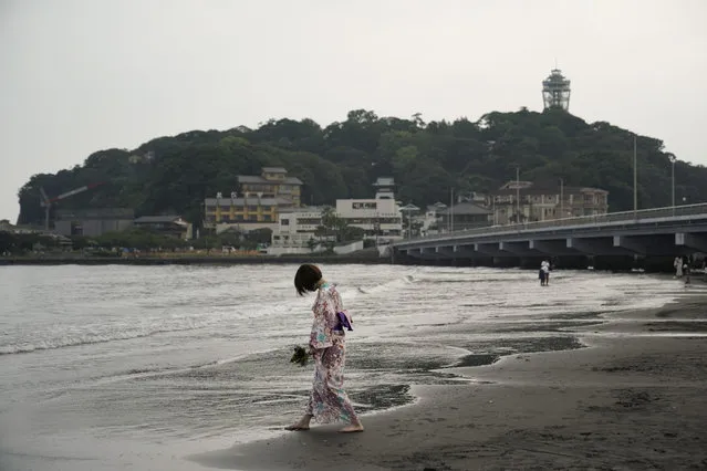 A woman wearing yukata strolls along the beach near Enoshima Island in Fujisawa, west of Tokyo, Thursday, Aug. 22, 2019. The island is set to host sailing events at the Tokyo 2020 Olympics. (Photo by Jae C. Hong/AP Photo)