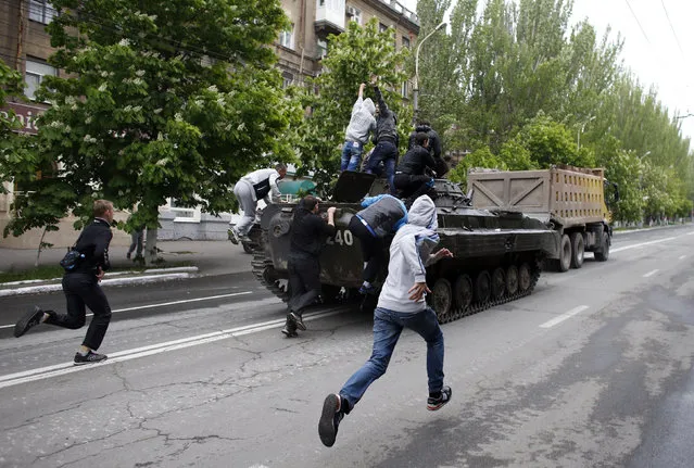 Children run to climb on a broken armoured vehicle of Ukrainian forces as is taken away by pro-Russian militants in Mariupol May 9, 2014. Ukrainian security forces killed about 20 pro-Russian rebels who tried to seize control of police headquarters in the eastern port city of Mariupol on Friday, the Interior Minister said. (Photo by Marko Djurica/Reuters)