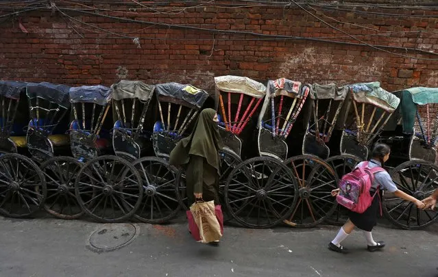 A woman and a schoolgirl walk past a row of parked hand-pulled rickshaws in Kolkata, India, May 3, 2016. Picture taken May 3, 2016. (Photo by Rupak De Chowdhuri/Reuters)