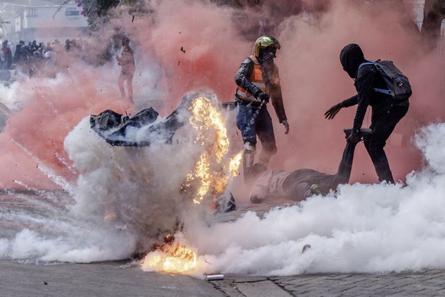 A tear gas canister explodes as protesters try to help injured people outside the Kenya Parliament during a nationwide strike to protest against tax hikes and the Finance Bill 2024 in downtown Nairobi, on June 25, 2024. Kenyan police shot dead one protester near the country's parliament Tuesday, a rights watchdog said as demonstrators angry over proposed tax hikes breached barricades and entered the government complex, where a fire erupted. The mainly Gen-Z-led rallies, which began last week, have taken President William Ruto's government by surprise, with the Kenyan leader saying over the weekend that he was ready to speak to the protesters. (Photo by Luis Tato/AFP Photo)