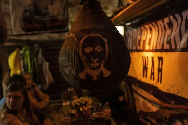 A boxing bag with a drawing of Russian President Vladimir Putin's face hangs inside a bar in downtown Lviv, western Ukraine, Tuesday, March 22, 2022. (Photo by Bernat Armangue/AP Photo)