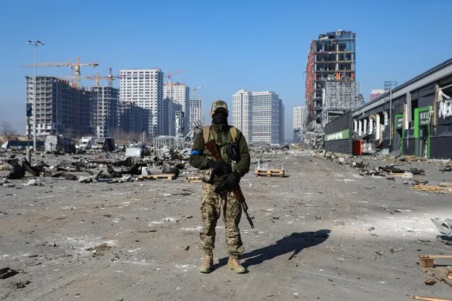 A soldier is pictured outside a shopping mall ruined as a result of a missile strike carried out by the Russian troops in the Podilskyi district of Kyiv, capital of Ukraine on March 29, 2022. (Photo by Yuliia Ovsiannikova/Avalon)