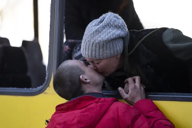 Mykolaivna Shankarukina, 54, kisses her son from inside a damaged bus as she is leaving from the Ukrainian Red Cross center in Mykolaiv, southern Ukraine, on Monday, March 28, 2022. Shankarukina and her family evacuated from Sablagodante village in the Mykolaiv district that have been attacked by the Russian army. She and a grandson are going to Odesa and from there to Prague, as the rest of the family, her son, daughter in law and a grandson will stay in Mykolaiv in a center for displaced residents. (Photo by Petros Giannakouris/AP Photo)