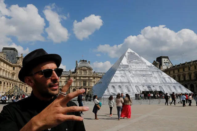 French artist JR stands in front of his lastest work, an image of the facade of Paris' Louvre covering the museum's pyramid entrance. May 25, 2016. (Photo by Pascal Rossignol/Reuters)