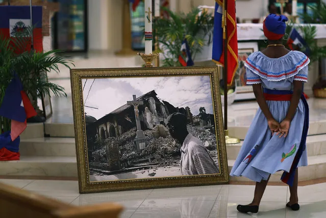 A dancer takes part in a dance near a framed picture of  a church that was destroyed by the massive 2010 Earthquake in Haiti during a service at the Notre Dame D'Haiti Catholic Church as they celebrate Haitian Flag day in the Little Haiti neighborhood on May 18, 2017 in Miami, Florida. The prayer service also touched on the church's concern about the outcome of the decision on extending the Temporary Protected Status for Haitians living in the United States because it would possibly mean friends and families would be sent back to Haiti. 50,000 Haitians have been eligible for TPS and now the Trump Administration has until May 23 to make a decision on extending TPS for Haitians or allowing it to expire on July 22. (Photo by Joe Raedle/Getty Images)