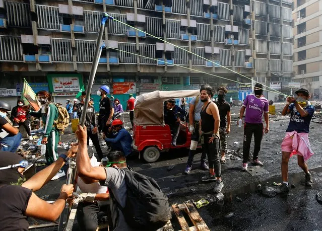 An Iraqi demonstrator uses a slingshot during ongoing anti-government protests in Baghdad, Iraq on November 14, 2019. (Photo by Alaa al-Marjani/Reuters)