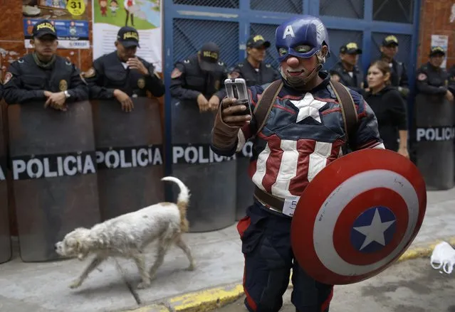 A clown dressed as comic book character Captain America chats with a friend as he takes part in a march celebrating Peruvian Clown Day in Lima, Peru, Thursday, May 25, 2017. Hundreds of professional clowns gather annually on this date to honor the late and beloved “Tony Perejil”, who died on May 25, 1987, after spending years bed-ridden in a hospital. He was known as the Clown of the Poor because he would perform in impoverished neighborhoods to which he would donate a portion of his proceeds to improve the communities' infrastructures. (Photo by Martin Mejia/AP Photo)