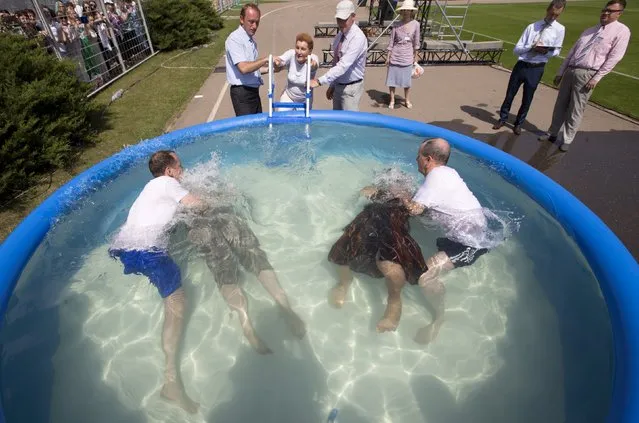Jehovah's Witnesses are baptized in a pool during a regional congress of Jehovah's Witnesses at Traktar Stadium in Minsk, Belarus, July 25, 2015. (Photo by Vasily Fedosenko/Reuters)