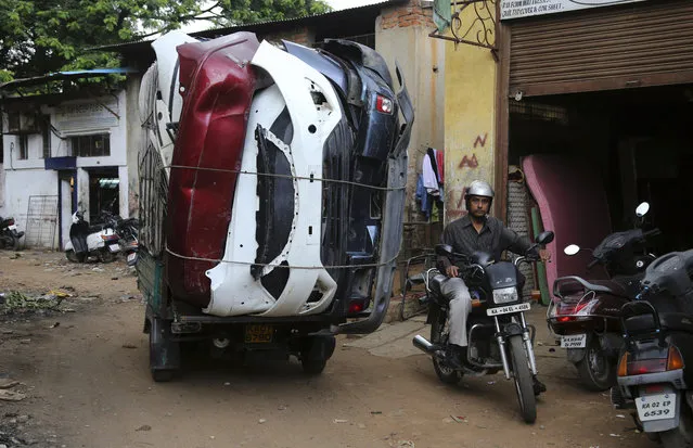 A person drives past a vehicle carrying automobile scrap at an industrial unit in Bangalore, India, Tuesday, May 31, 2016. India says its economy grew 7.6 percent in the financial year that ended March 31 and a swift 7.9 percent in the last quarter of the year keeping its position as the world's fastest growing major economy. (Photo by Aijaz Rahi/AP Photo)
