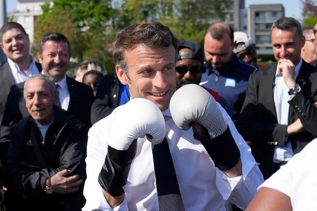 French President and La Republique en Marche (LREM) party candidate for re-election Emmanuel Macron wears boxing gloves as he meets a local boxer at the Auguste Delaune stadium on April 21, 2022 during a campaign visit in Saint-Denis, outside Paris. French voters head to the polls on April 24, 2022 for the second round of France's presidential election. (Photo by Francois Mori/Pool via AFP Photo)