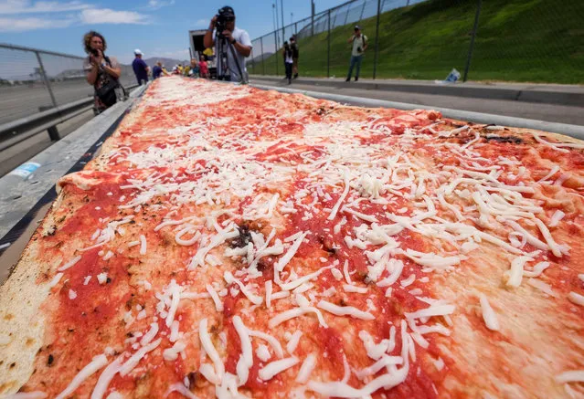 Volunteer work on a pizza during an attempt to make a 7,000' (2.13 km) to break the world record for longest pizza in Fontana, California, the United Staes on June 10, 2017. The longest pizza measures 1,853.88 m (6,082 ft 3.40 in) and was achieved by Napoli Pizza Village, in Naples, Italy, on 18 May 2016. (Photo  by Zhao Hanrong/Xinhua/Barcroft Images)