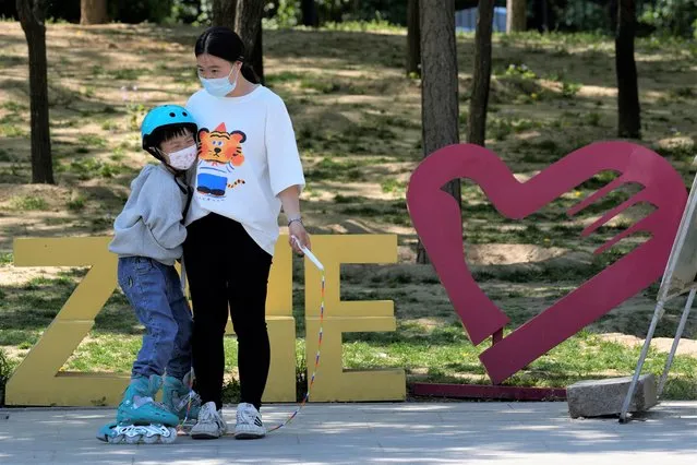 A woman and child enjoy their day at a park on Sunday, May 1, 2022, in Beijing. Many Chinese are marking a quiet May Day holiday this year as the government's zero-COVID approach restricts travel and enforces lockdowns in multiple cities. (Photo by Ng Han Guan/AP Photo)