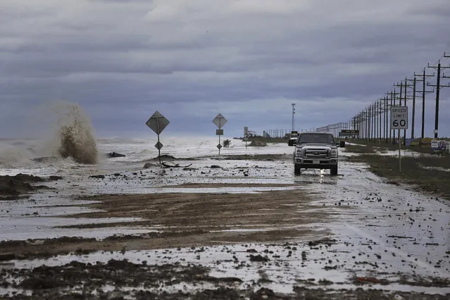 Vehicles navigate past waves and debris washing over State Highway 87 as Tropical Storm Cindy approaches Wednesday, June 21, 2017, in High Island, Texas. (Photo by Michael Ciaglo/Houston Chronicle via AP Photo)