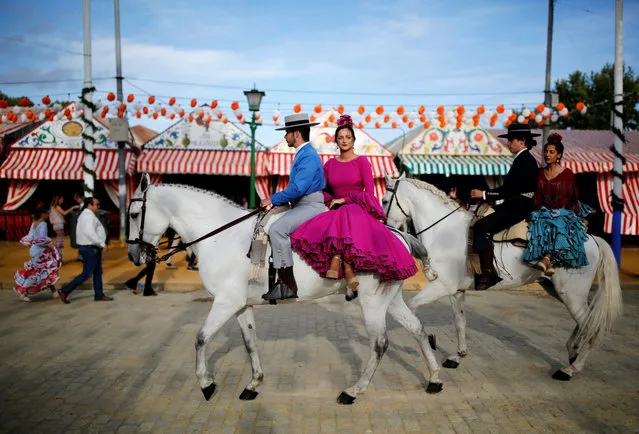 Riders wearing Andalusian outfits and women wearing sevillana dresses ride during the traditional Feria de Abril (April fair) in the Andalusian capital of Seville, southern Spain, May 9, 2019. The fair will run until May 11. (Photo by Marcelo del Pozo/Reuters)