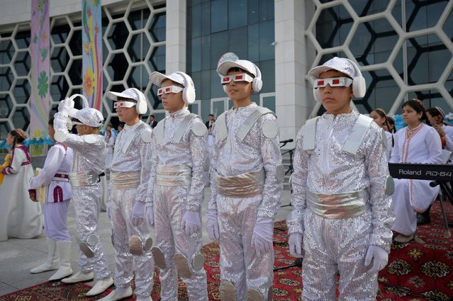 Children wait for the arrival of Turkmen President Serdar Berdymukhamedov prior to the opening of a children's medical centre as part of the events inaugurating the new city of Arkadag – named in honour of Turkmenistan's former leader Gurbanguly Berdymukhamedov – in Arkadag, some 30 kilometres (18 miles) outside the capital Ashgabat, on June 29, 2023. The reclusive Central Asian country bordering the Caspian Sea has been ruled by the Berdymukhamedov family for more than 16 years. Gurbanguly Berdymukhamedov officially stepped down as president of the ex-Soviet nation last year and was replaced by his son, Serdar Berdymukhamedov. (Photo by Natalia Kolesnikova/AFP Photo)