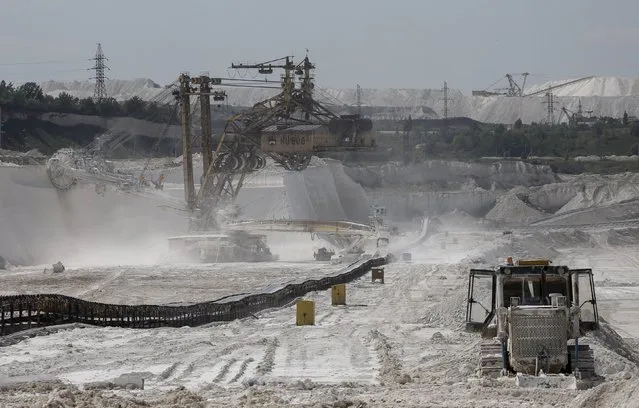 A rotary dredge (L) cuts the bedrock at an open-cast iron ore mine of the Stoilensky mining and concentration plant (GOK), owned by the Novolipetsk (NLMK) steel mill, in the city of Stary Oskol in Belgorod region, Russia, August 4, 2015. (Photo by Maxim Shemetov/Reuters)