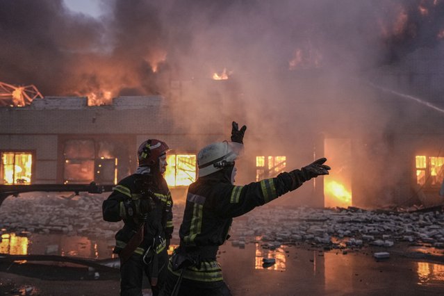 Ukrainian firefighters extinguish a blaze at a warehouse after a bombing in Kyiv, Ukraine, Thursday, March 17, 2022. Russian forces destroyed a theater in Mariupol where hundreds of people were sheltering Wednesday and rained fire on other cities, Ukrainian authorities said, even as the two sides projected optimism over efforts to negotiate an end to the fighting. (Photo by Vadim Ghirda/AP Photo)