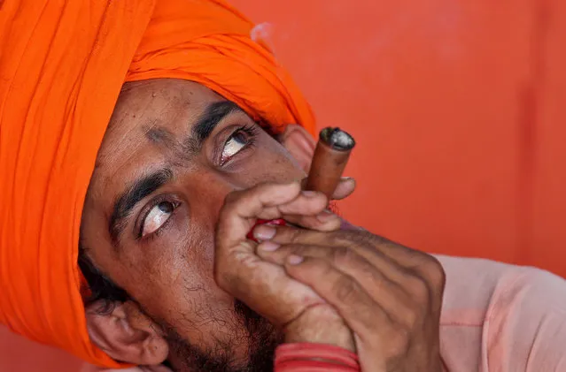 A Sadhu, or Hindu holy man, smokes a pipe at a base camp before registering for the annual pilgrimage to the Amarnath cave shrine where they worship an ice stalagmite that Hindus believe to be the symbol of Lord Shiva, in Jammu June 30, 2017. (Photo by Mukesh Gupta/Reuters)