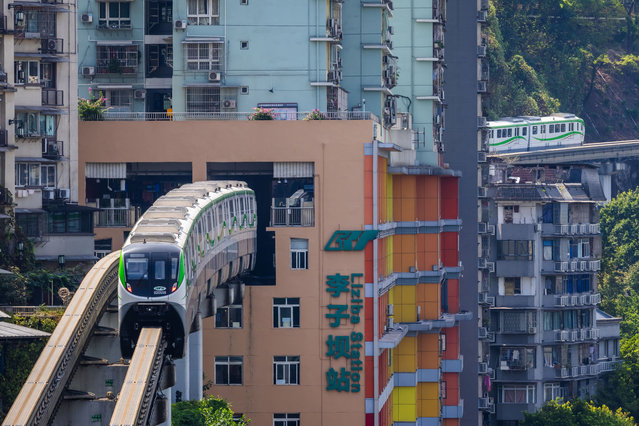 Two Chongqing Rail Transit monorail trains approach Liziba Station from opposite directions, showcasing the unique design where trains pass through a residential building, on September 17, 2024, in Chongqing, China. (Photo by Cheng Xin/Getty Images)