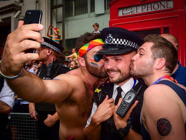 Two men pose for selfies with a police officer as revellers take part in London Pride, the Lesbian, Gay, Bisexual, and Transgender (LGBT) parade in London, Britain, 08 July 2017. The annual event aims to raise awareness and campaign for equality on LGBT issues. (Photo by Pete Maclaine/EPA)