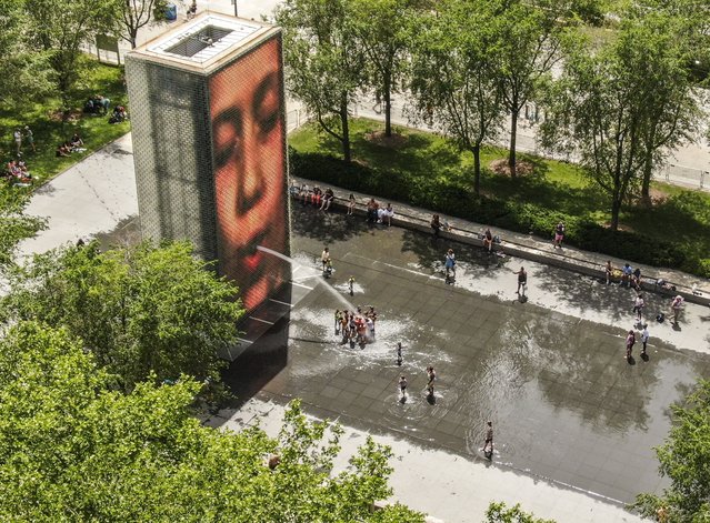 An aerial photo made with a drone shows people seeking relief from a dangerous heat wave at the Crown Fountain and wading pool in Chicago, Illinois, USA, 15 June 2022. Heat warnings and advisories have been issued that affect more than 100,000 people as record breaking temperatures threaten lives and power grids. (Photo by Tannen Maury/EPA/EFE)
