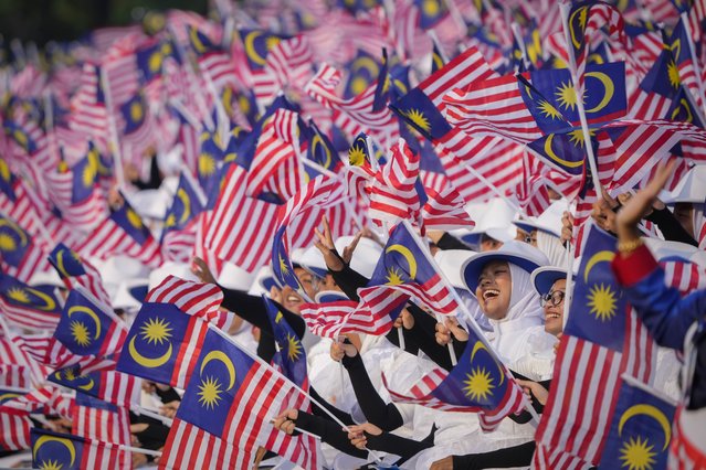 Students wave national flags during the National Day parade in Putrajaya, Malaysia, Saturday, August 31, 2024. (Photo by Vincent Thian/AP Photo)