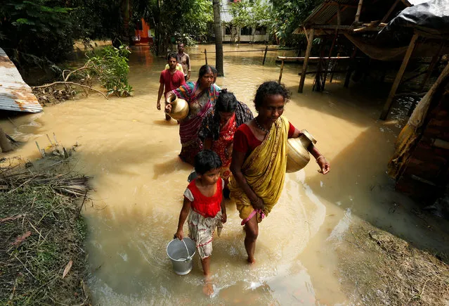 People wade through a flooded road to collect drinking water in Howrah district, West Bengal, India August 2, 2017. (Photo by Rupak De Chowdhuri/Reuters)